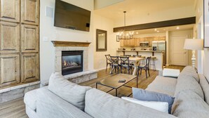 A spacious living room with a fireplace, a large sofa, and a dining area with chairs and a table. - Walk to Lift: Arrowhead Ski Condo w/ Pool Access! (Edwards)