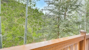 A wooden deck with a view of a forested area. - Walk to Lift: Arrowhead Ski Condo w/ Pool Access! (Edwards)