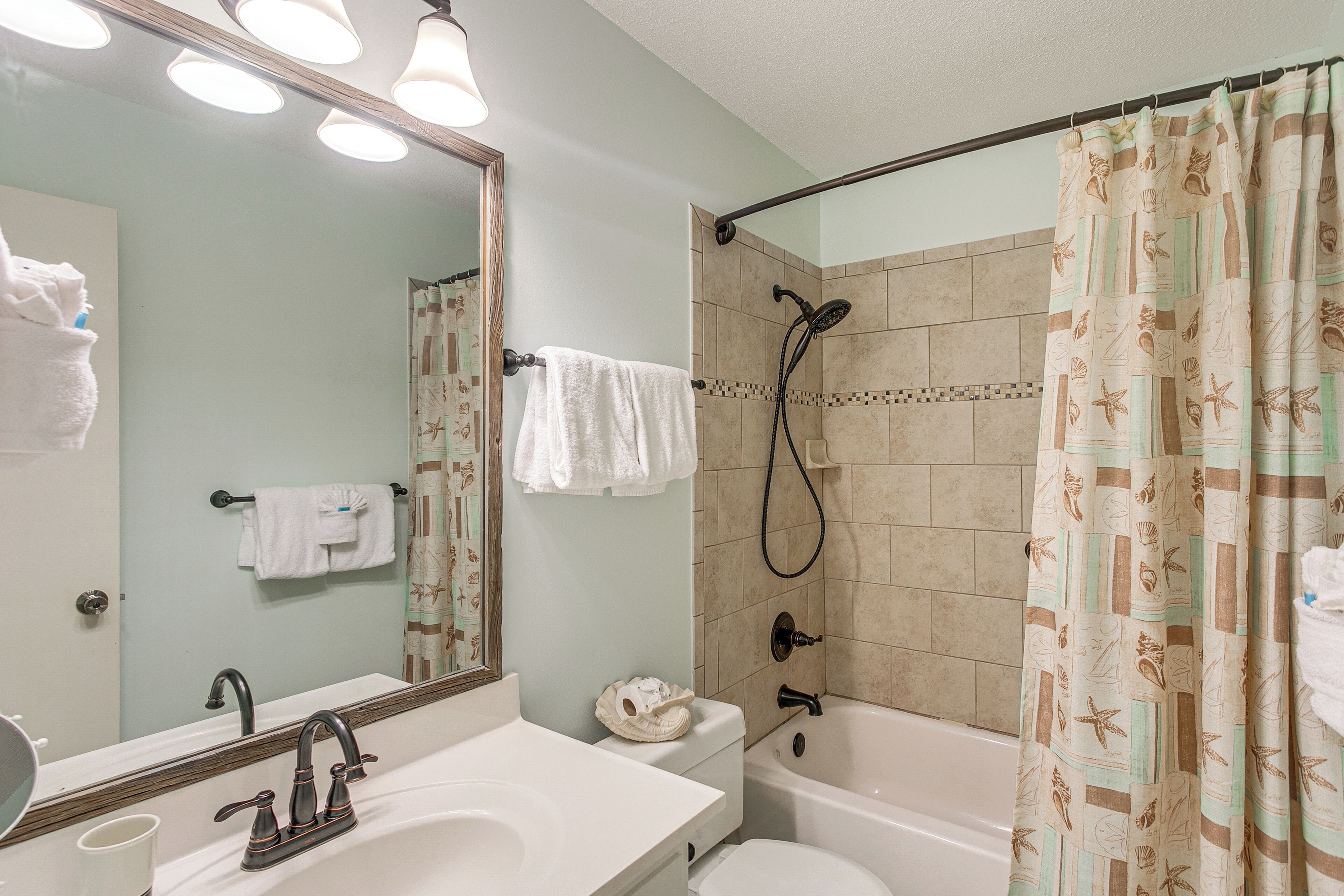 A bathroom with a sink, mirror, and shower.