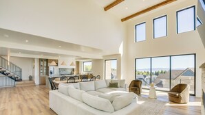 A spacious living area with a large sectional sofa, a dining table with chairs, and a kitchen in the background. - Luxe Retreat w/ Theater Room: Walk to Bear Lake! (Garden City)