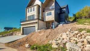 A modern two-story house with a stone facade, a garage, and a balcony. - Luxe Retreat w/ Theater Room: Walk to Bear Lake! (Garden City)