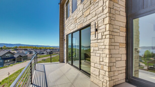 A modern building with stone facade and large glass windows, offering a view of a residential area. - Luxe Retreat w/ Theater Room: Walk to Bear Lake! (Garden City)