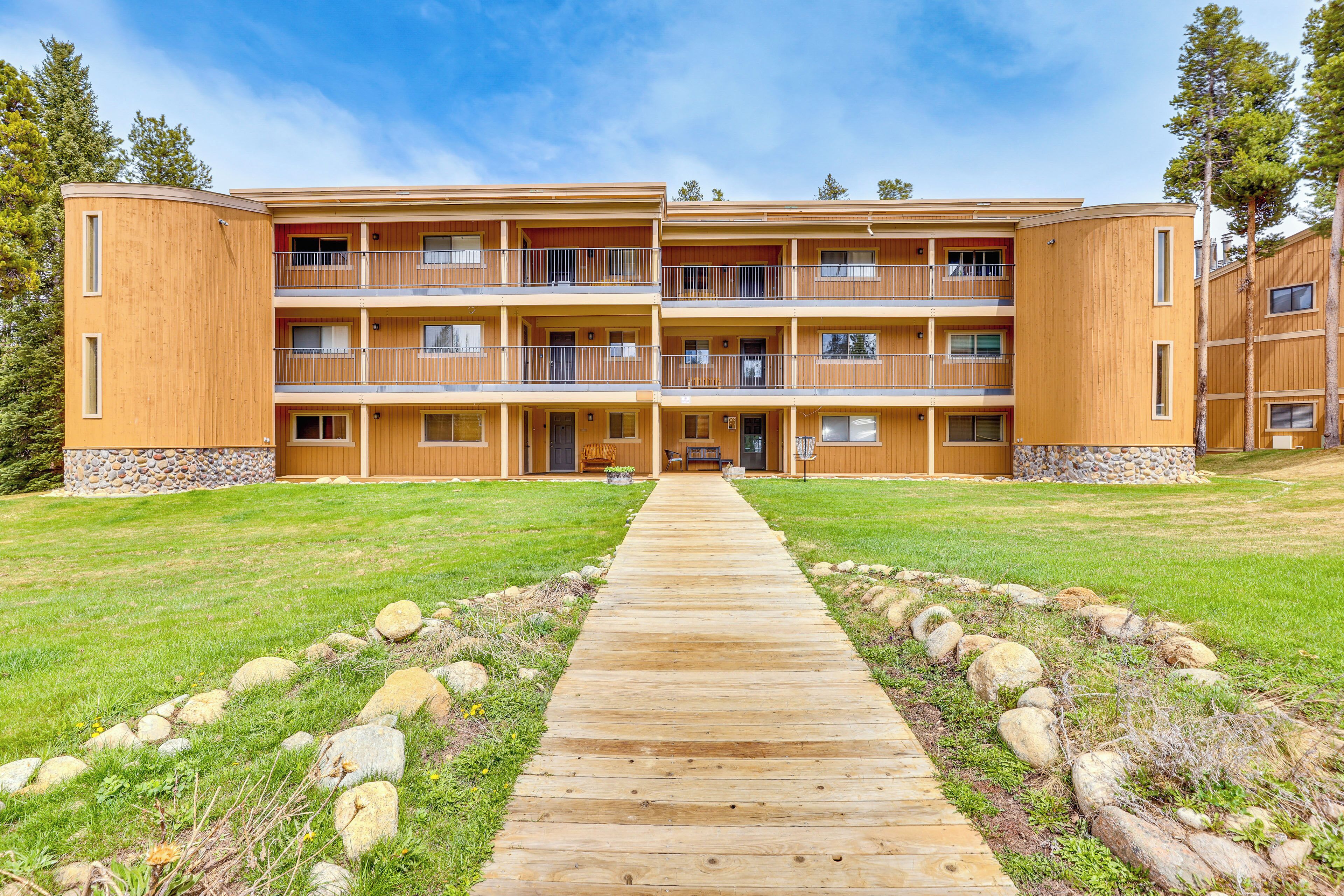 A multi-story wooden building with balconies, a central walkway, and a stone base.