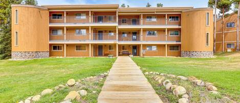 A multi-story wooden building with balconies, a central walkway, and a stone base.