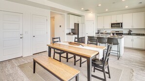 Una cocina moderna con armarios blancos, una mesa de comedor de madera y un microondas empotrado.