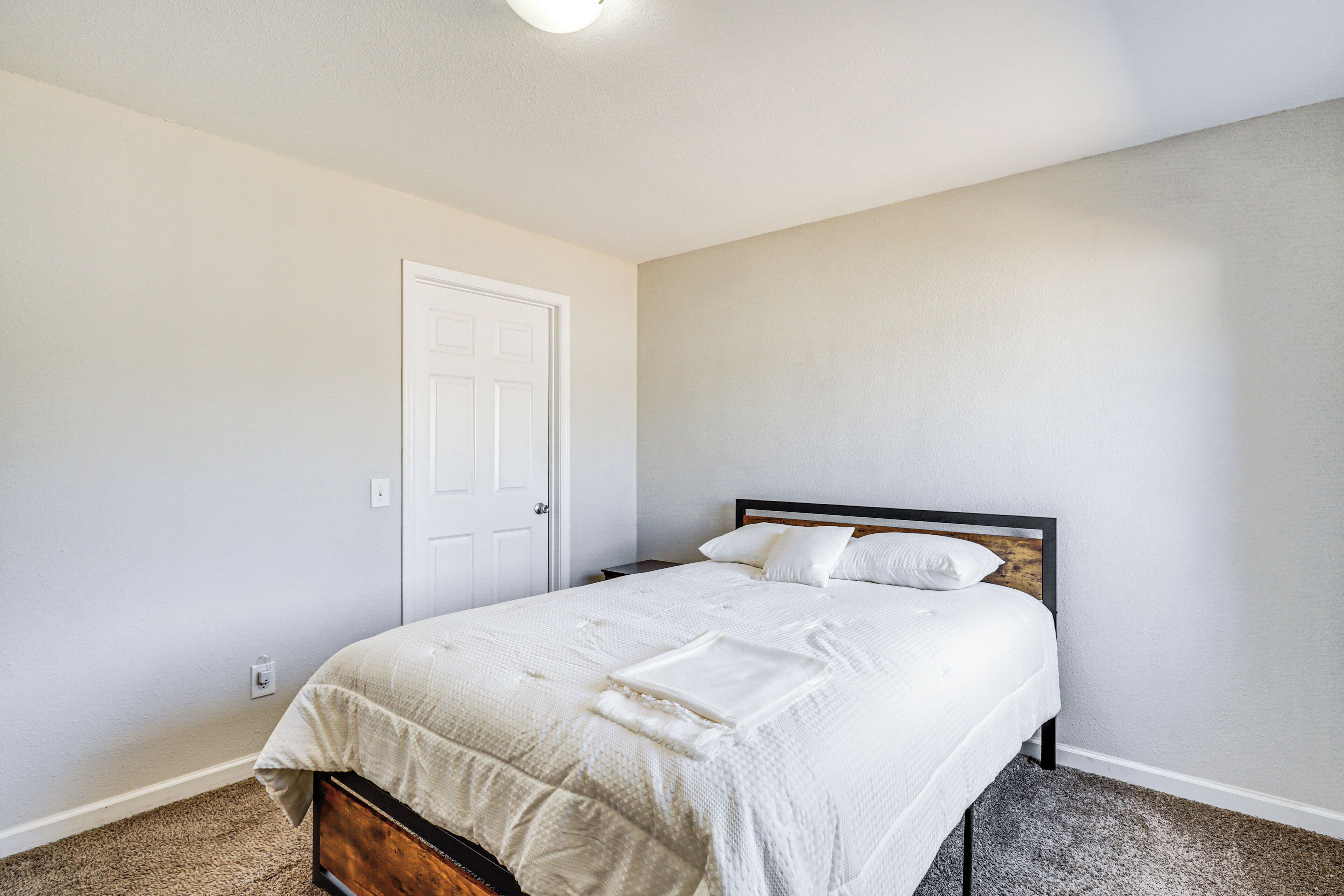 Un dormitorio con cama, una puerta y suelo alfombrado.