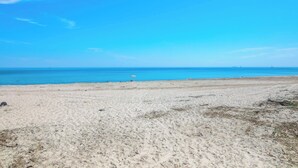 A sandy beach with a clear blue sky and calm sea. - Steps to the Sand! Plymouth Beach Cottage (Plymouth)