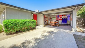 A garage with a red door, a small patio area with a table and chairs, and a Canadian flag hanging on the wall. - Family-friendly Clovis Home w/ Gas Grill + Patio! (Clovis)