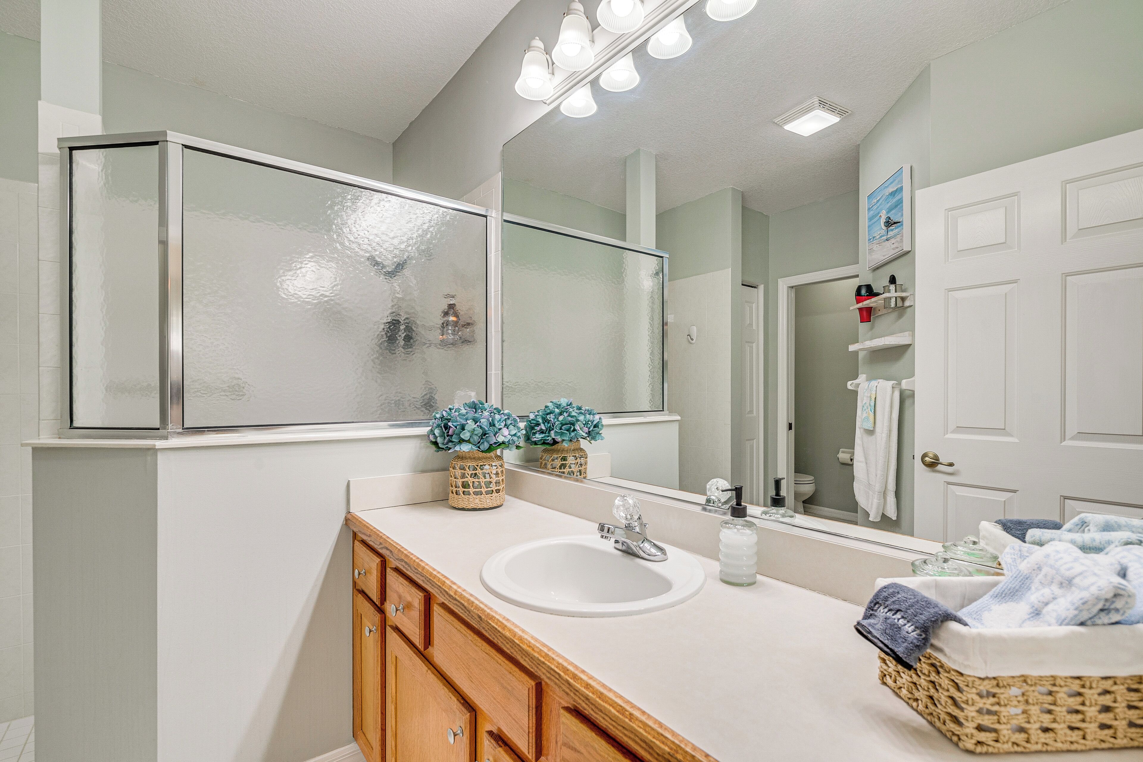 A bathroom with a white sink, wooden vanity, and a large mirror.
