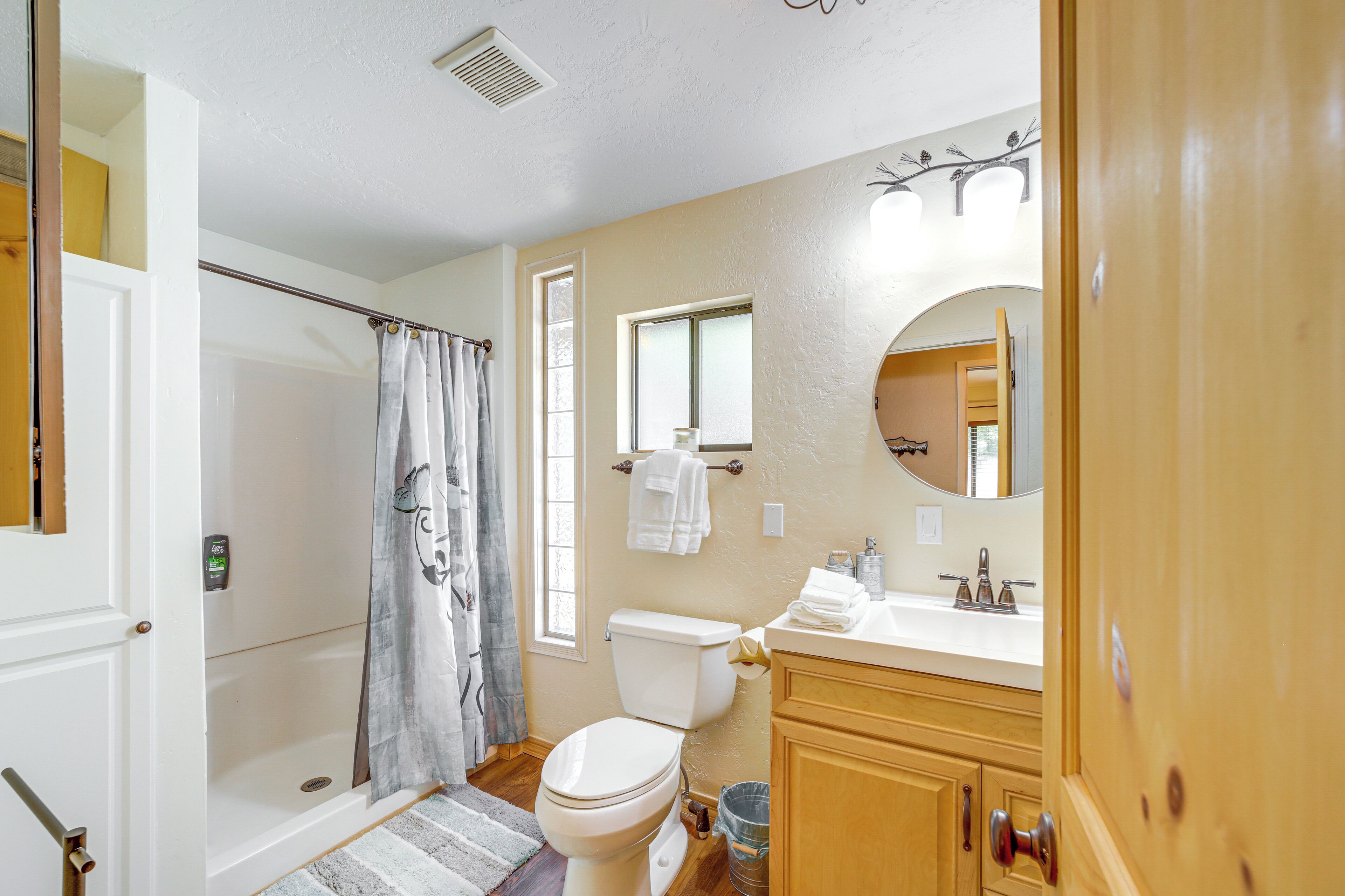 A bathroom with a shower, toilet, sink, and mirror.