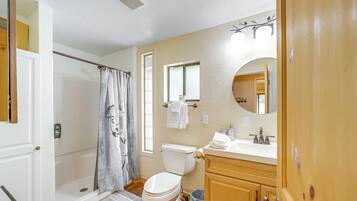 A bathroom with a shower, toilet, sink, and mirror.
