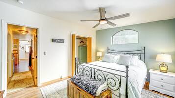 A bedroom with a bed, bedside tables, a nightstand, a ceiling fan, and a wooden bench.