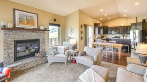 A spacious living room with a stone fireplace, a dining area, and a kitchen with modern appliances. - Spearfish Retreat w/ Fireplace + Mountain Views! (Spearfish)