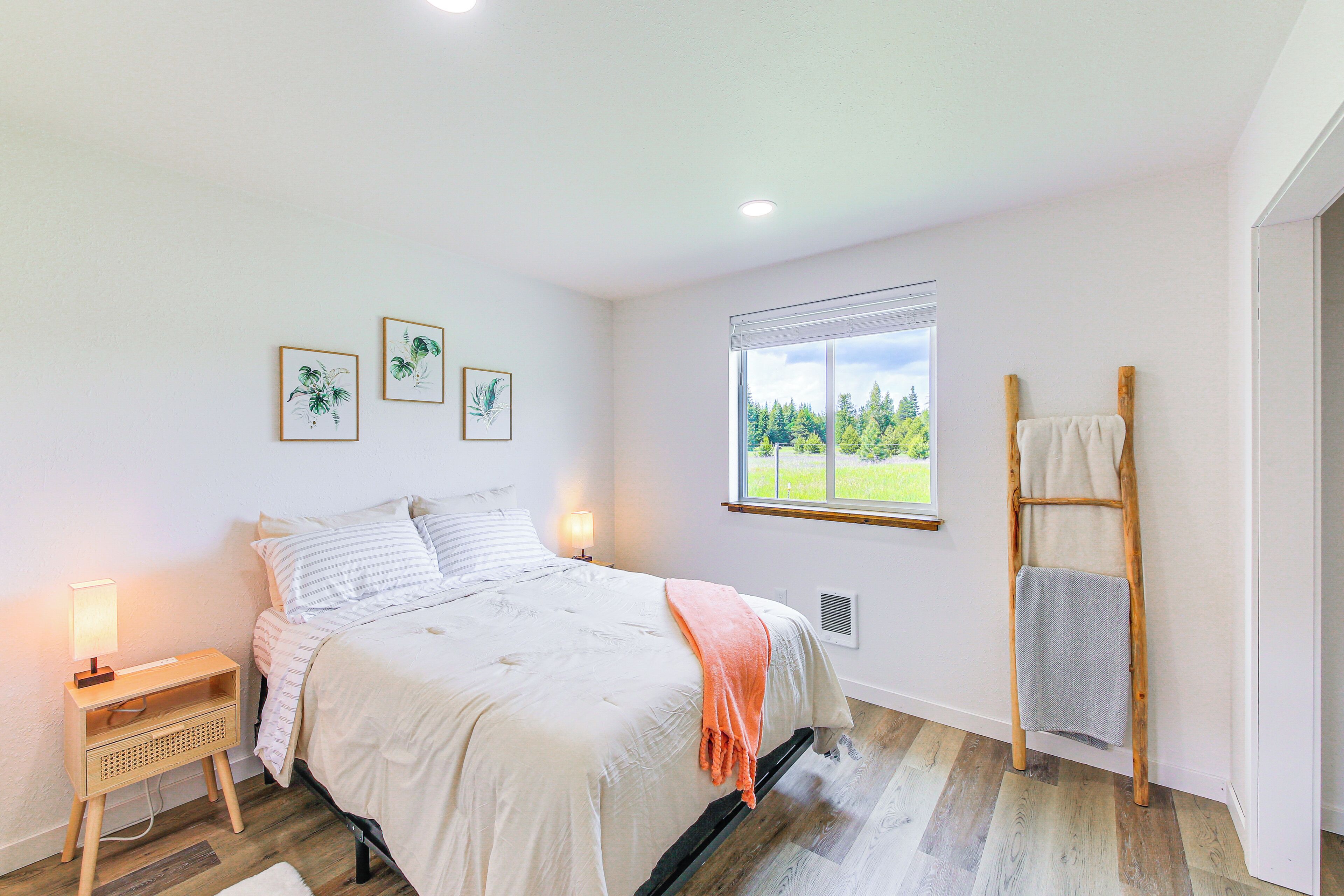 A bedroom with a bed, bedside lamps, a window with a view, and a wooden ladder.