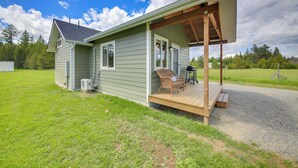 Une maison de plain-pied avec un porche couvert, une petite terrasse et une cour gazonnée.