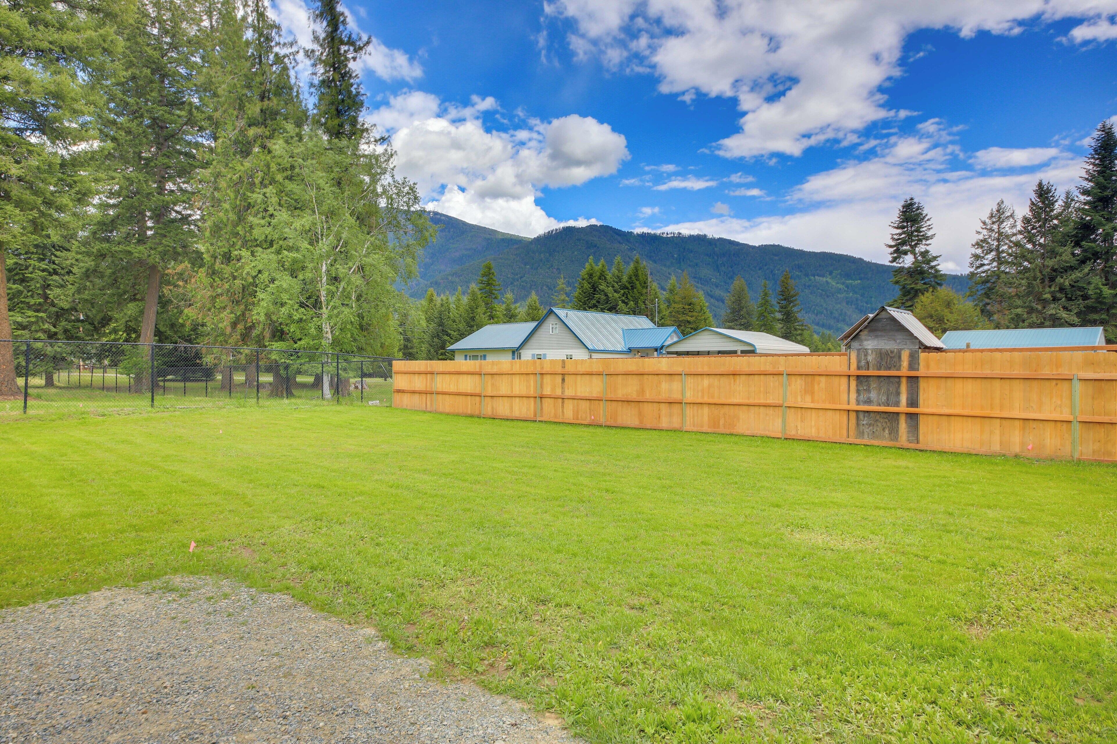 A fenced property with multiple wooden cabins, a grassy field, and a mountain backdrop.
