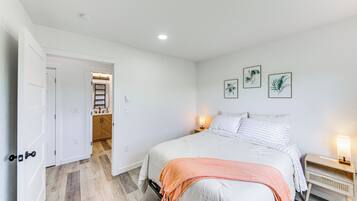 Un dormitorio con una cama, lámparas de noche y una puerta que da al baño.