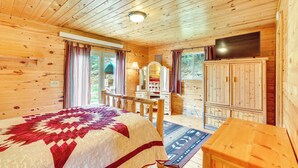 A wooden cabin bedroom with a bed, a TV, a desk, and a wardrobe. - Wraparound Deck & Grill: Deadwood Cabin (Deadwood)