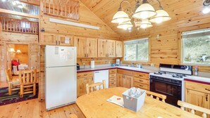 A wooden cabin with a kitchen featuring a refrigerator, stove, and wooden cabinets. - Wraparound Deck & Grill: Deadwood Cabin (Deadwood)