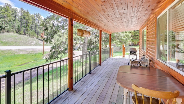 A wooden deck with a table and chairs, overlooking a grassy area and trees. - Pets Welcome: Cozy Cabin w/ Deck in Deadwood! (Deadwood)