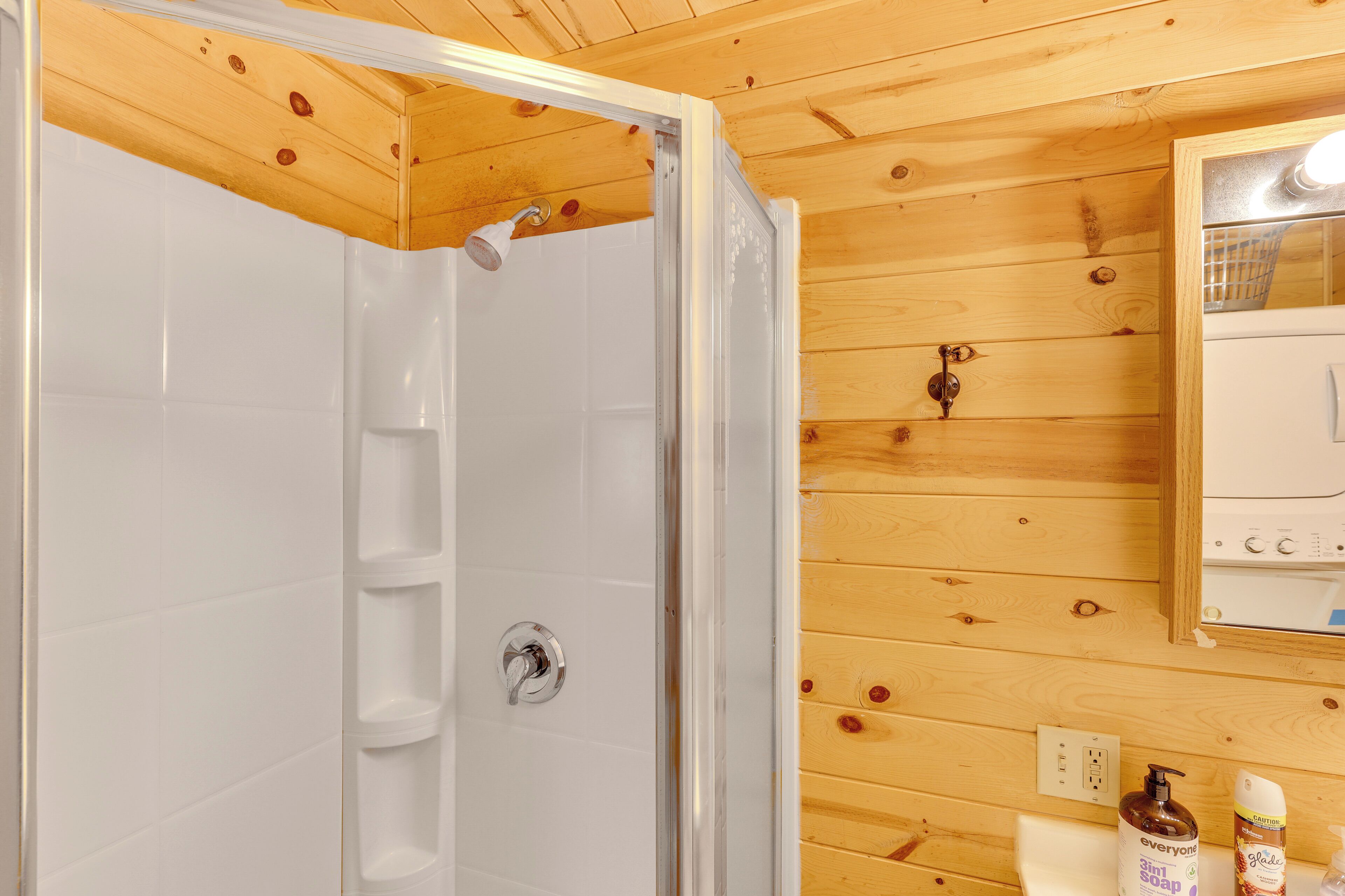 Ein Badezimmer einer Holzhütte mit Dusche, Waschbecken und Spiegel.