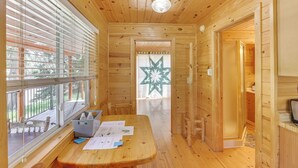 A wooden cabin interior with a wooden table, papers, a bottle, and a star-patterned curtain. - Pets Welcome: Cozy Cabin w/ Deck in Deadwood! (Deadwood)