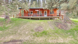 A cabin with a porch, surrounded by trees. - Pets Welcome: Cozy Cabin w/ Deck in Deadwood! (Deadwood)