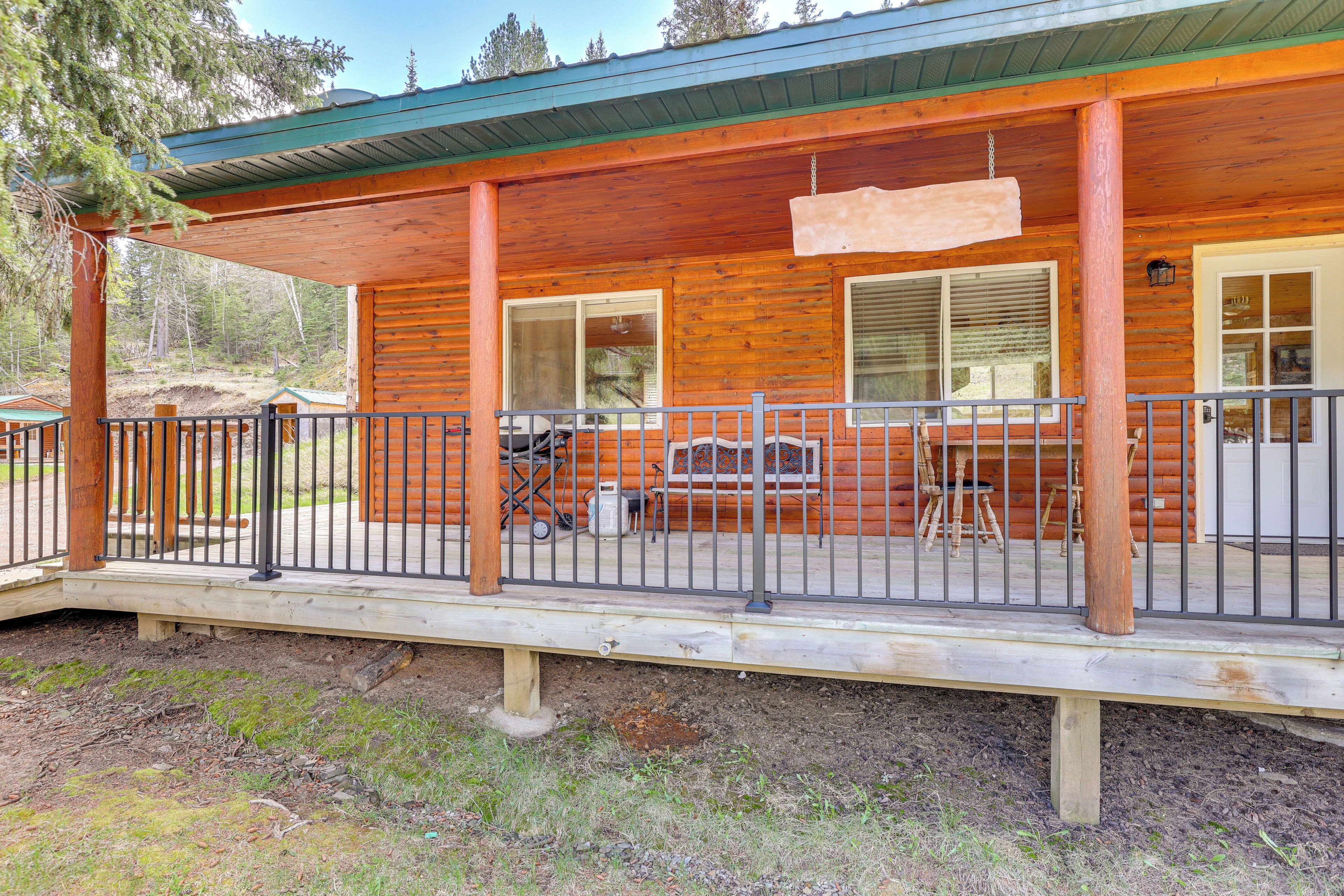 A wooden cabin with a covered porch, large windows, and a fenced deck area.