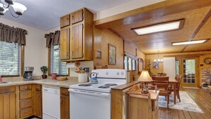 Una cocina con armarios de madera, una estufa blanca y una zona de comedor con una mesa y sillas.