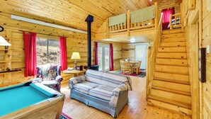 A wooden cabin interior with a pool table, sofa, and staircase leading to a loft. - Hike, Unwind & Bring Your Pet: Deadwood Cabin! (Deadwood)