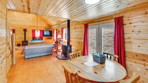 A wooden cabin interior with a dining area, a sofa, a television, and a fireplace. - Hike, Unwind & Bring Your Pet: Deadwood Cabin! (Deadwood)