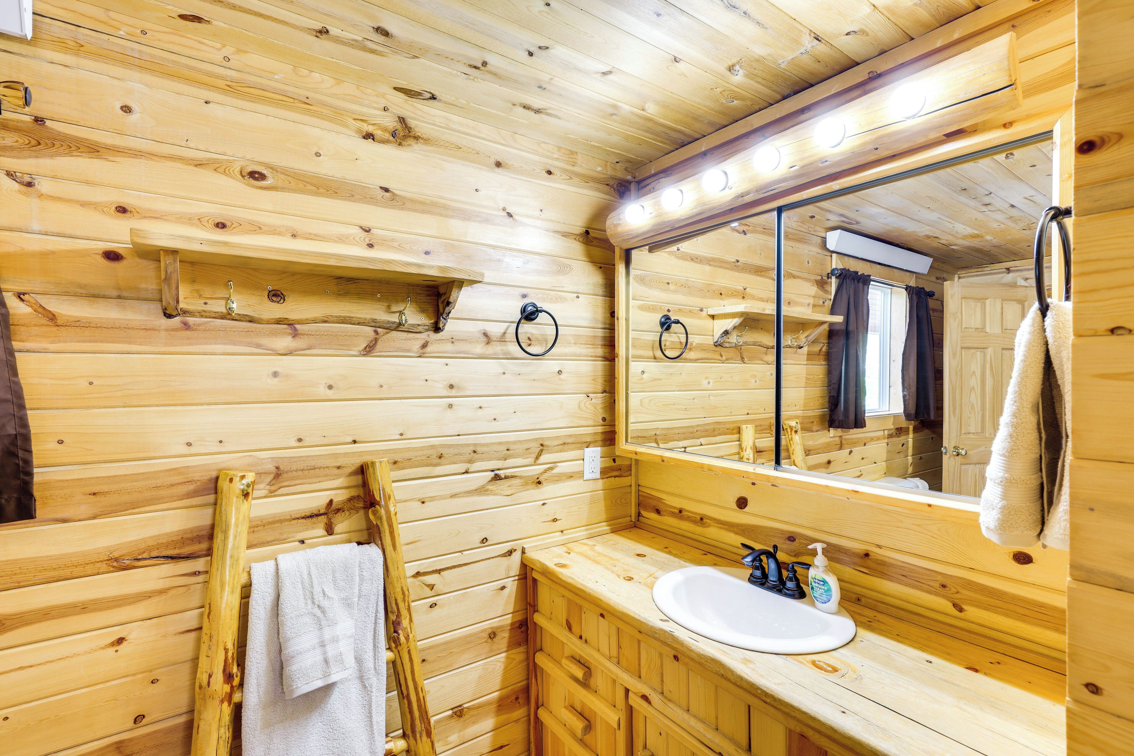 A wooden cabin bathroom with a wooden vanity, sink, and mirror.