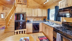 L'intérieur d'un chalet en bois comprend une cuisine, un coin repas et un escalier.
