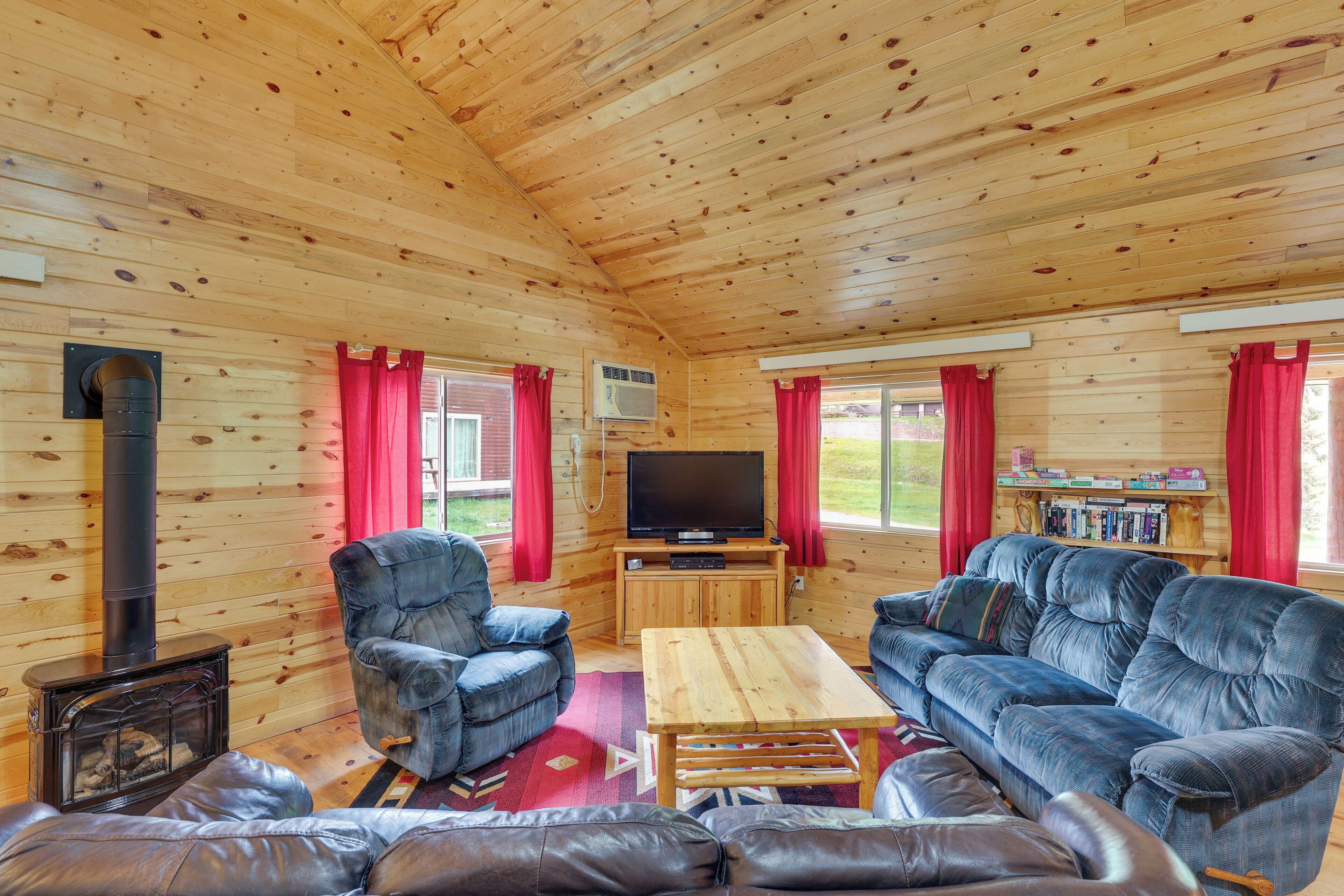A cozy cabin interior with a wooden interior, a fireplace, a television, and seating arrangements.