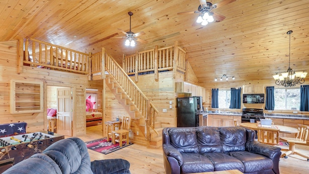 Une cabane en bois spacieuse comprenant un salon avec un canapé en cuir, un coin repas avec une table en bois et une cuisine équipée d’appareils modernes.
