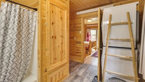 L’intérieur d’une cabane en bois comprend une douche, une armoire en bois, une échelle et un lave-linge.