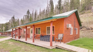 Une cabane en rondins dotée d’une véranda, d’un espace extérieur aménagé pour s’asseoir et d’une rampe d’accès pour les personnes à mobilité réduite.