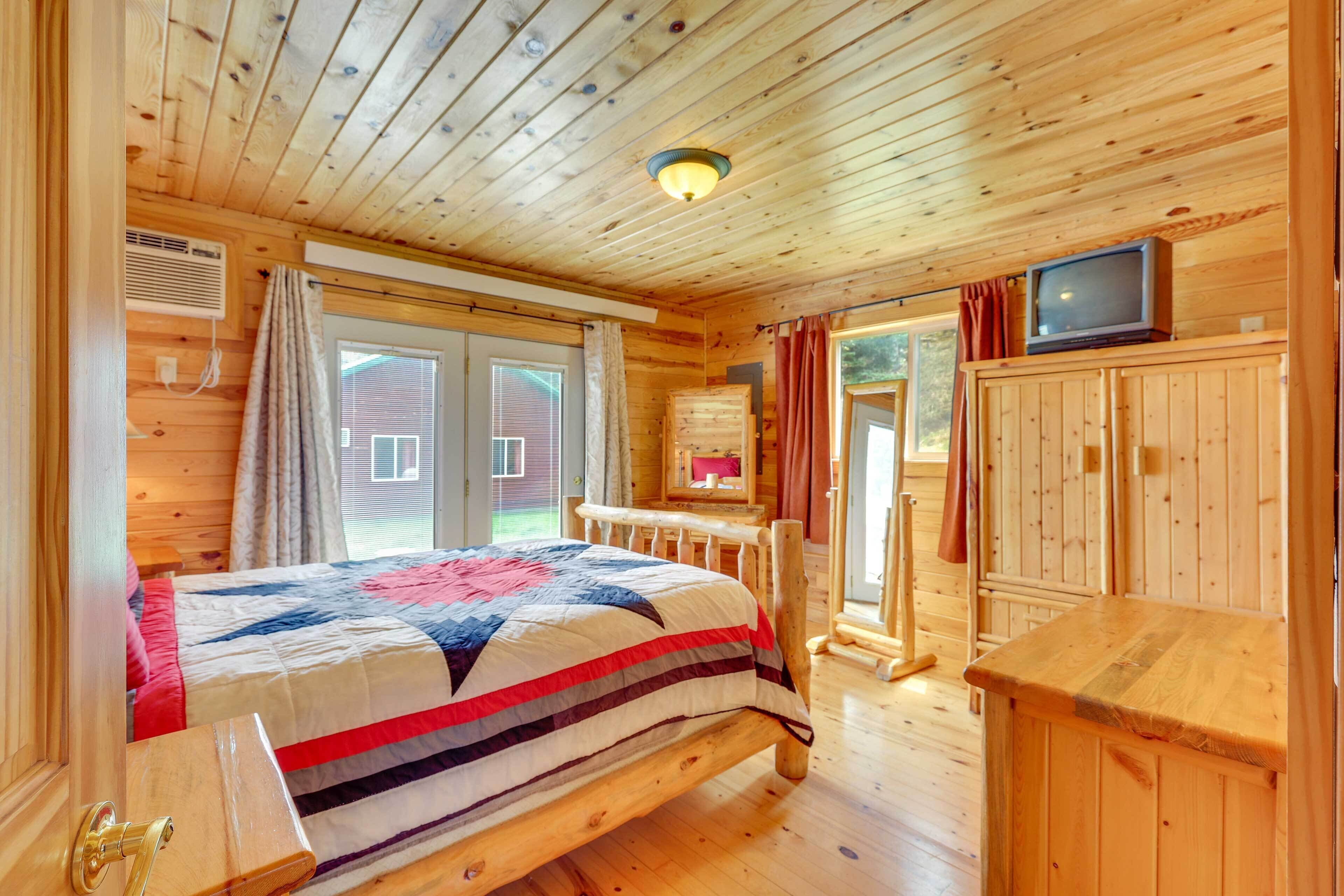 Quarto de cabana de madeira com cama, televisão e armário de madeira.