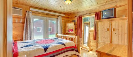 Quarto de cabana de madeira com cama, televisão e armário de madeira.