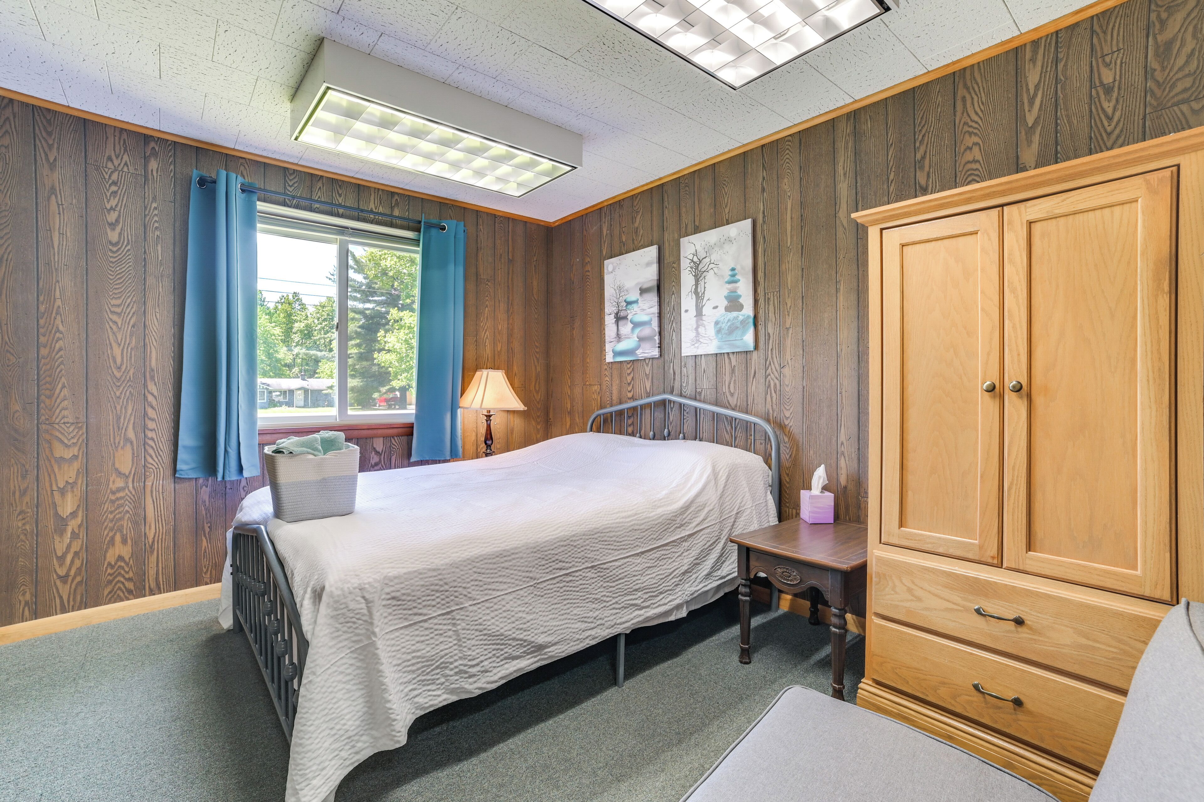 A bedroom with a bed, wooden wardrobe, and a window with curtains.