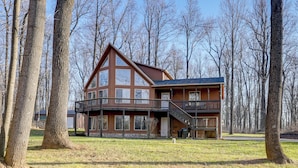 A two-story log cabin with a balcony, surrounded by trees. - Winter Linden Escape: Family Home & Gym (Linden)