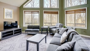 A living room with a large TV, two sofas, a coffee table, and large windows with blinds. - Winter Linden Escape: Family Home & Gym (Linden)