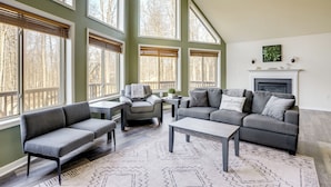 A spacious living room with a high ceiling, large windows, a fireplace, and a cozy seating area. - Winter Linden Escape: Family Home & Gym (Linden)