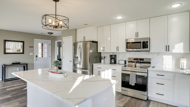 A modern kitchen with white cabinetry, stainless steel appliances, and a marble island. - Winter Linden Escape: Family Home & Gym (Linden)