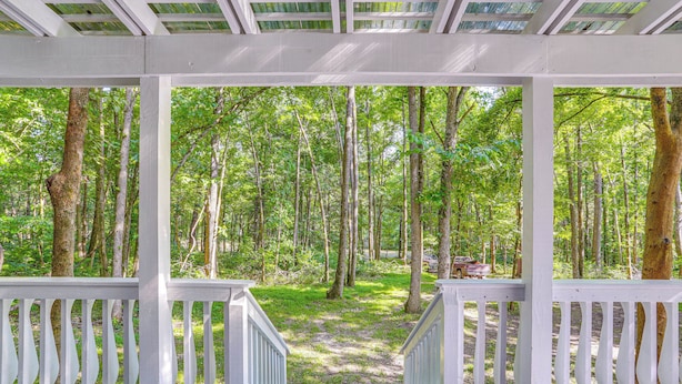 A covered wooden deck with a view of a forested area. - Secluded Vacation Rental Bordering Creek! (Mountain View)
