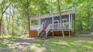 A cabin with a covered porch, a staircase, and a red chair. - Secluded Vacation Rental Bordering Creek! (Mountain View)