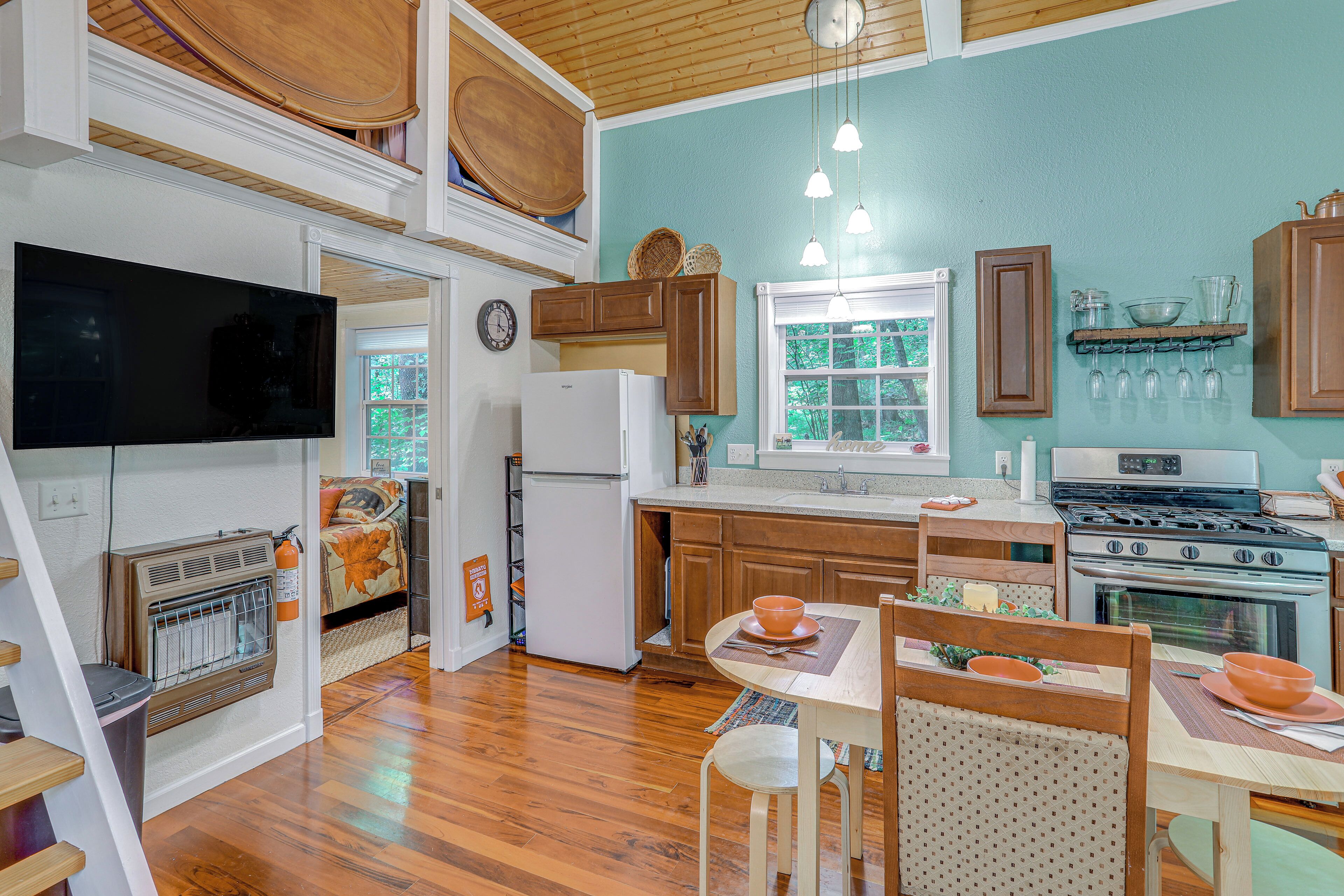 A kitchen with wooden cabinets, a refrigerator, a stove, and a dining area with a table and chairs.