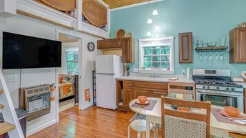 A kitchen with wooden cabinets, a refrigerator, a stove, and a dining area with a table and chairs.