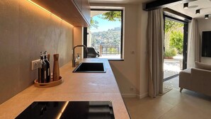 A modern kitchen with a large island, built-in appliances, and a view of a balcony. - A DAY AT LA VILLA BOMPARD: RELAXATION AND ADVENTURE AWAIT (Marseille)