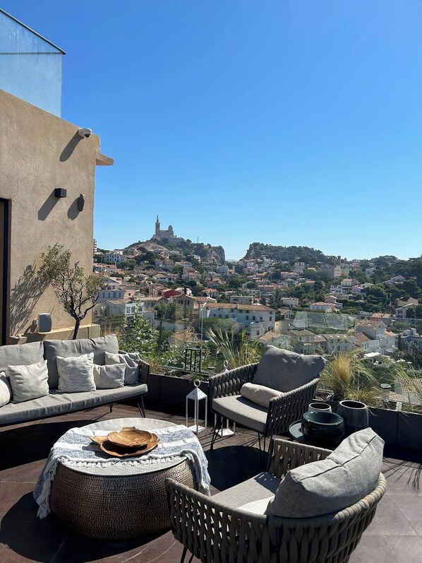 Une terrasse sur le toit, aménagée avec du mobilier d’extérieur, offrant une vue sur le paysage urbain et donnant sur un bâtiment surmonté d’un dôme.